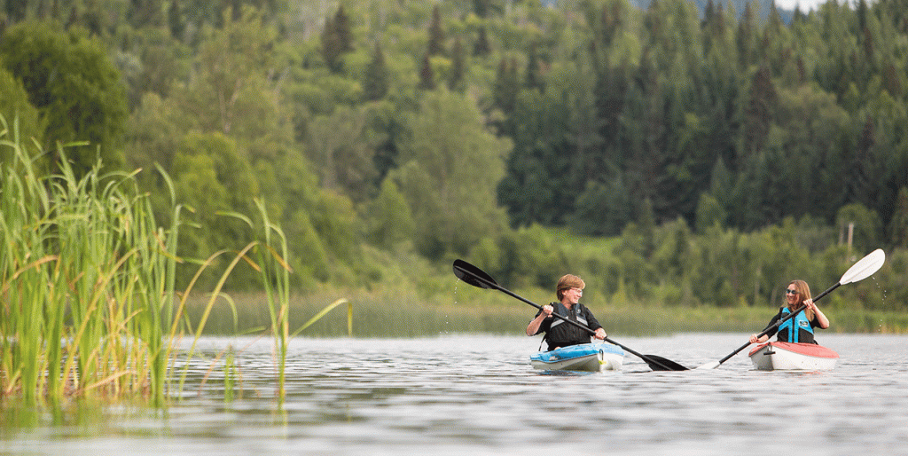 Two women conversing while kayaking side by side.